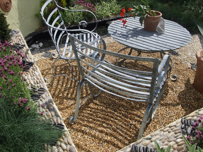 A small gravel patio with two chairs and a table