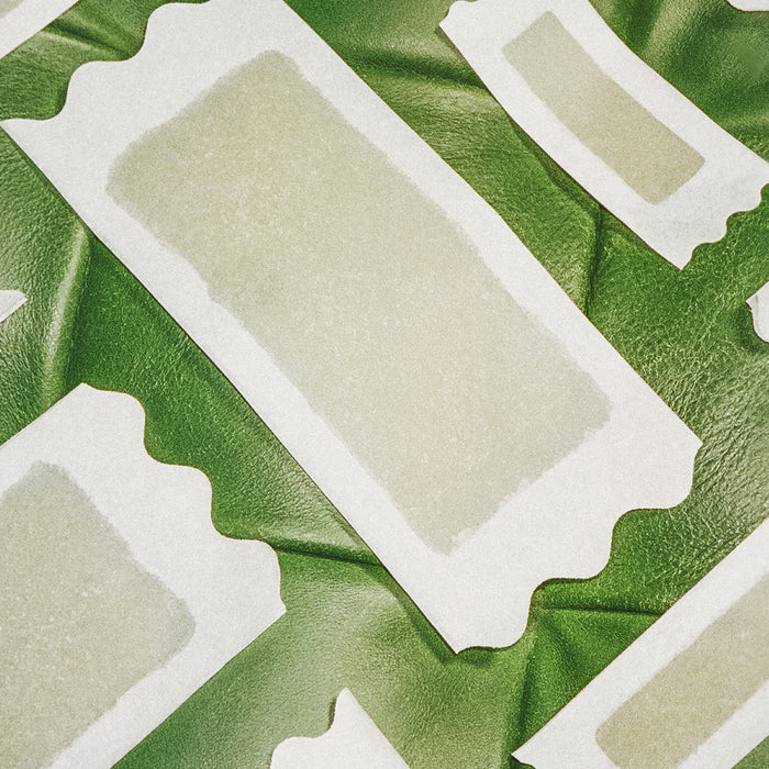 Different sized Flamingo Wax strips on a green leather background