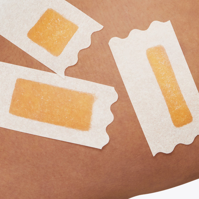 Closeup of a womans thigh with three Flamingo Wax strips applied