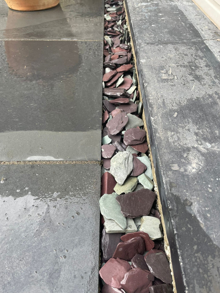 A garden patio with plum slate chippings filling the edges.